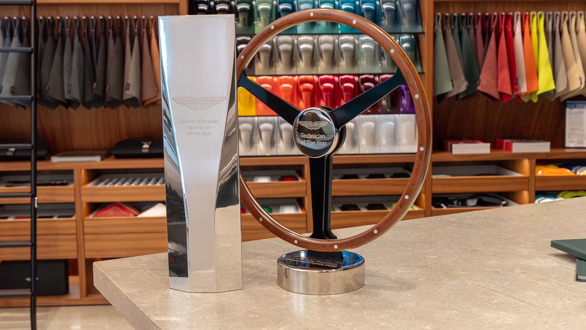 Die beiden Trophäen „Global Aftersales Technician of the Year“ und „Technician of the Year“ mit Holzlenkrad im Aston Martin Showroom
