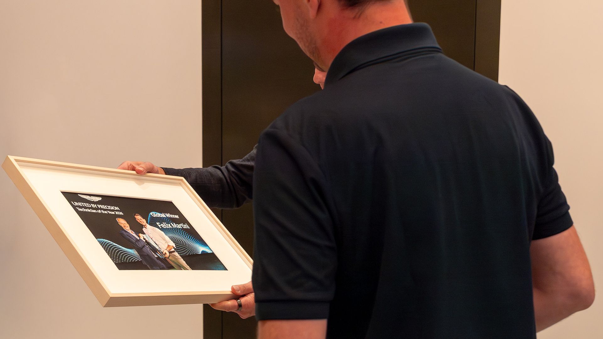 Felix Martini betrachtet die gerahmte Urkunde „Technician of the Year 2026 – Global Winner“