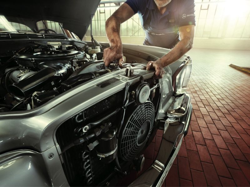 Mann mit öligen Armen arbeitet an Oldtimer Motor