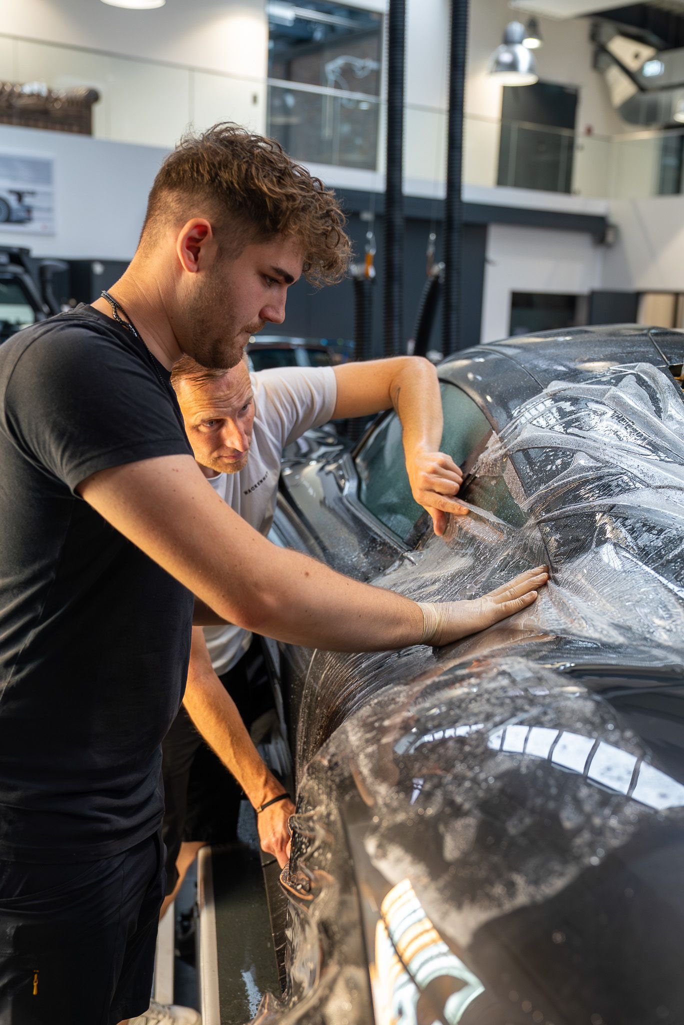 Zwei Mitarbeiter bringen eine Lackschutzfolie am Fahrzeug an