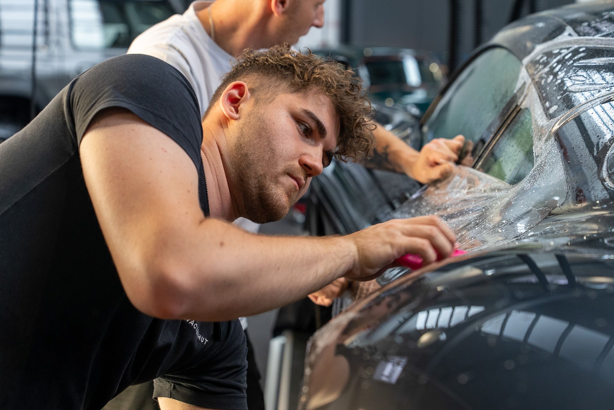 Zwei Mitarbeiter bringen eine Lackschutzfolie am Fahrzeug an