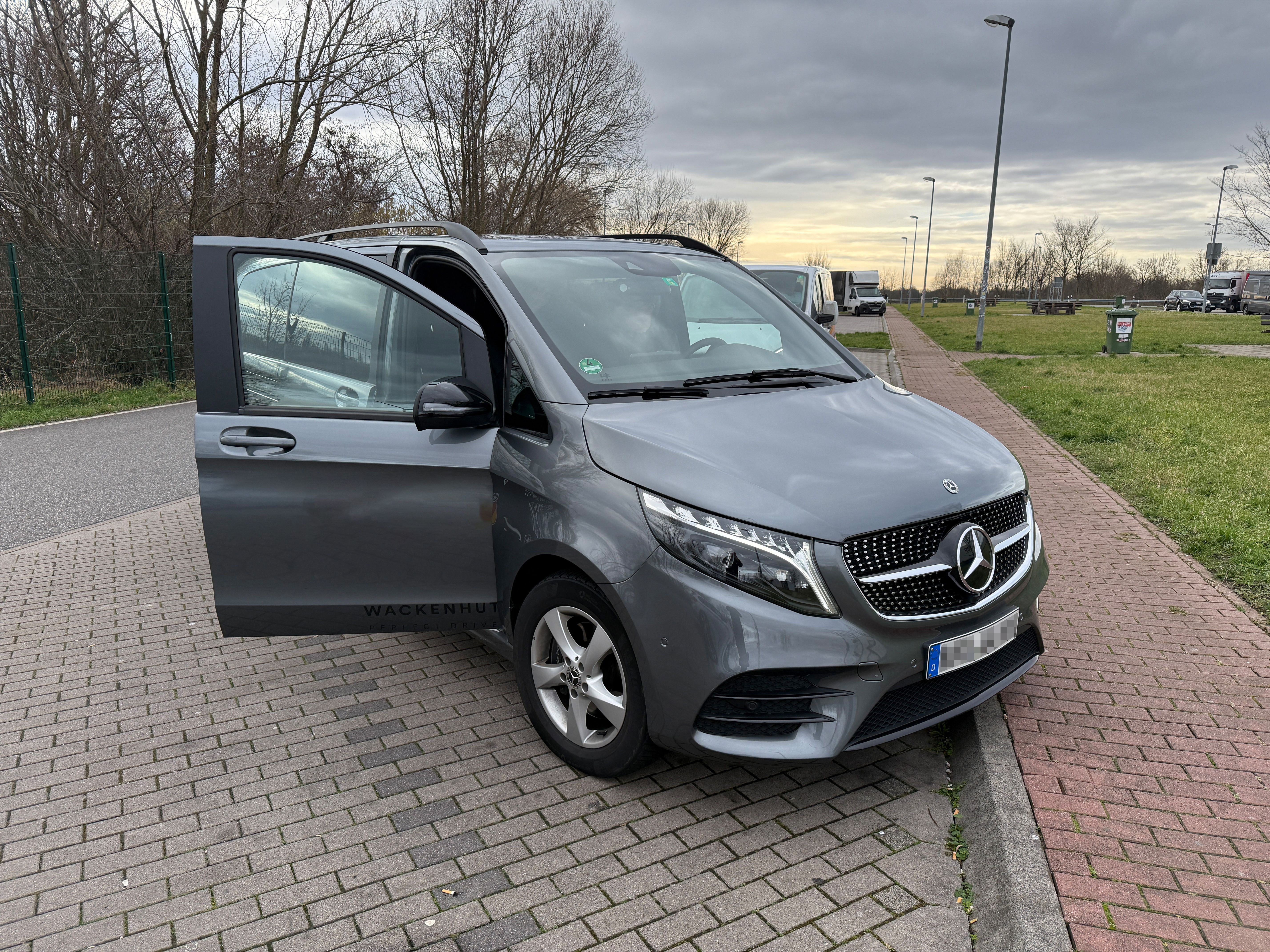 V-Klasse steht auf einem Parkplatz mit geöffneter Beifahrertür.