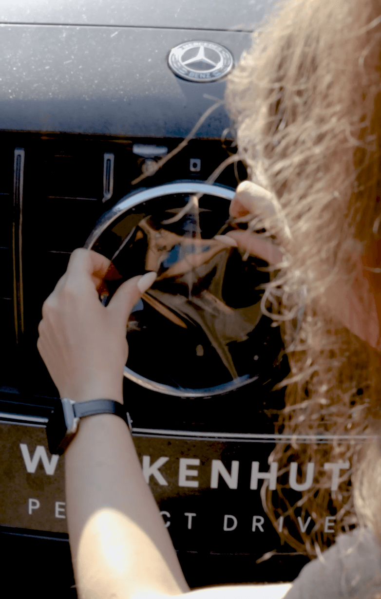 Frau bringt Lackschutzfolie am Mercedes-Benz Stern an