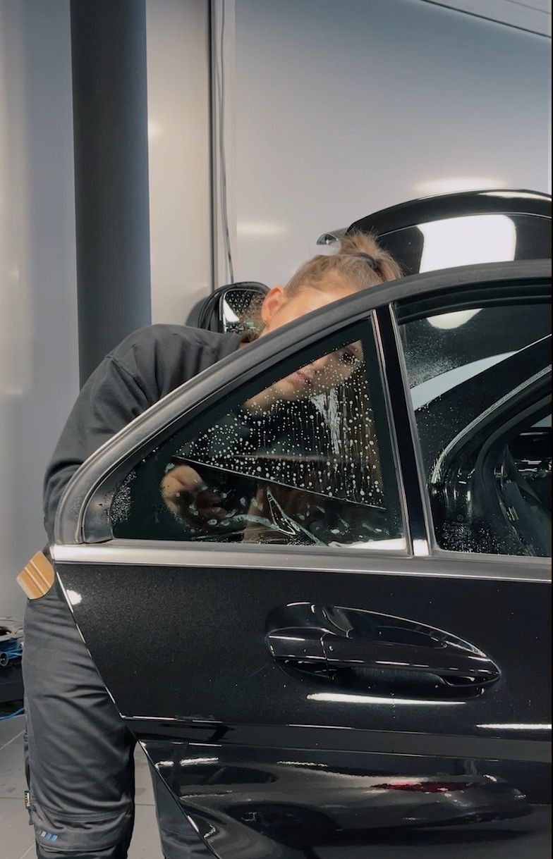 Frau tönt die Scheibe an einer schwarzen Autotür