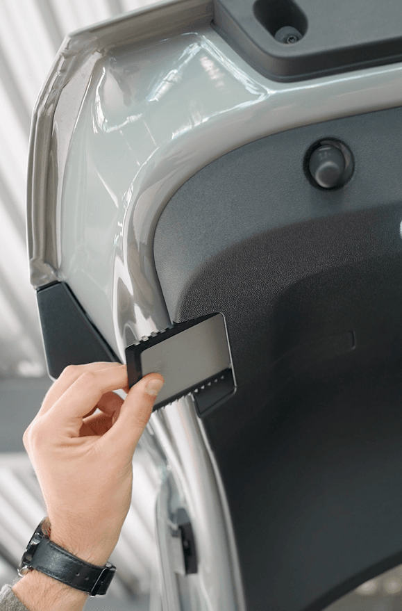 Detailbild von dem versteckten Eiskratzers in der Heckklappe des Skoda Enyaq.